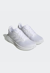 Scarpe da ginnastica bianche realizzate in tessuto a rete con superficie testurizzata, dotate di lacci piatti, tre strisce sui lati e una suola ammortizzata.