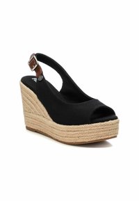 Zapato cuña negro de lona con punta abierta y talón descubierto, que presenta una correa marrón en el tobillo y una suela de plataforma de yute texturizada.