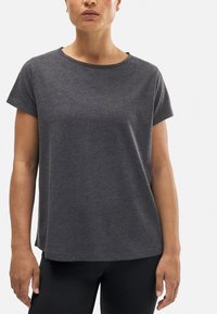 Camiseta gris de manga corta con escote redondo y ajuste relajado. Textura suave y aberturas laterales en el dobladillo para mayor comodidad en el movimiento.