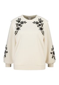 Crèmekleurige trui met zwarte bloemige borduursels op de schouders en mouwen. Zachte textuur, ronde halslijn en geribbelde boorden aan de zoom.