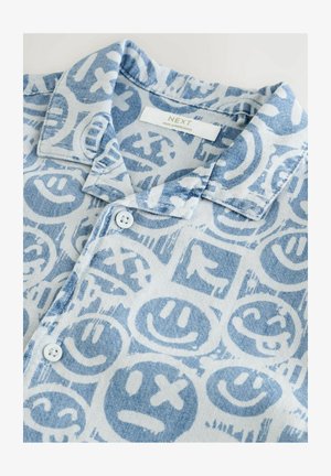 Cămașă cu mânecă scurtă dintr-un material moale, având un fundal albastru deschis cu modele grafice și fețe zâmbitoare albe și albastre mai închise, cu detalii cu nasturi.
