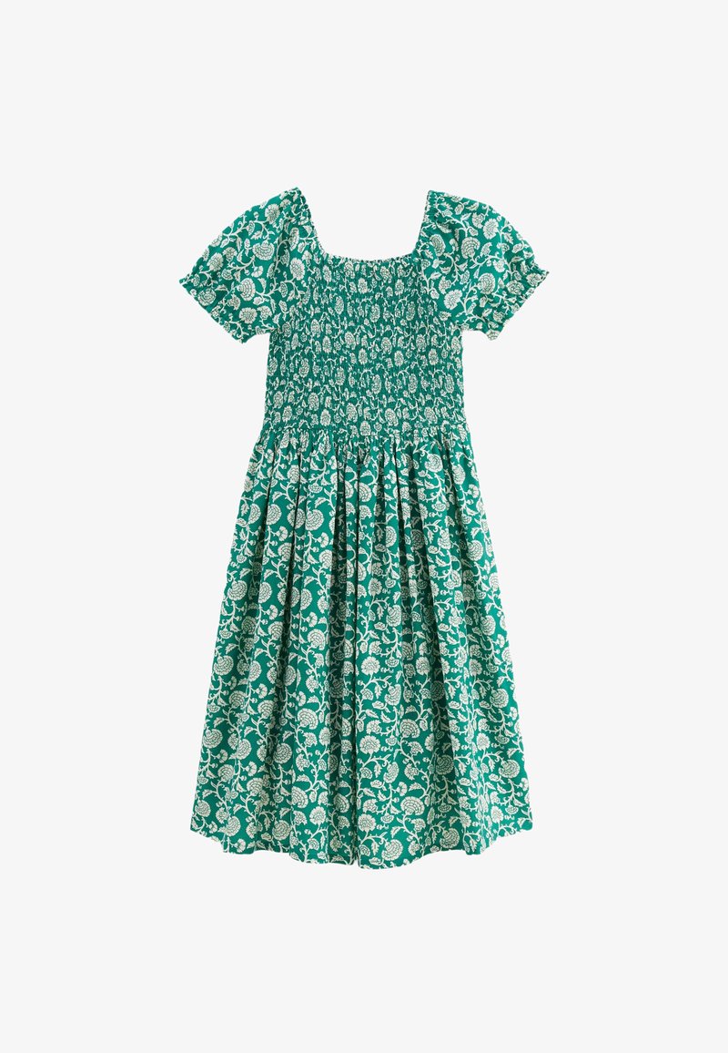 Robe florale verte avec des manches courtes bouffantes, un décolleté carré et un corps smocké. Présente des motifs de feuilles et de fleurs blanches sur toute la surface.