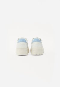 Sneaker bianchi e azzurri chiaro con tomaia in suede testurizzato, suola spessa e design semplice. Gli accenti includono una leggerissima curva del tacco e il branding.