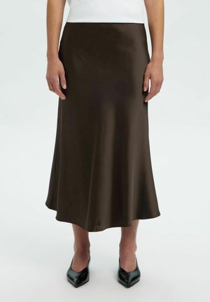 Gonna midi in satin marrone con una forma svasata, texture liscia e una silhouette fluida. Indossata con tacchi a punta neri.