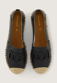 Black slip-on shoes with a braided jute accent at the toe and a decorative bow detail on the front. Soft material with a flat sole.