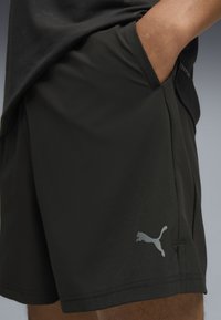 Sorte atletiske shorts lavet af letvægtsstof. Har et diskret Puma-logo på benet og sidelommer, med en glat tekstur.