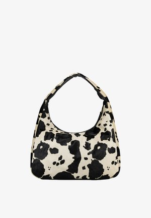 Sac à bandoulière imprimé vache noir et blanc avec une poignée supérieure incurvée et une forme rectangulaire arrondie sur un fond blanc.