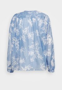 Blusa azul clara com padrão floral branco, mangas longas, corte descontraído e detalhe franzido nas costas. Tecido macio e leve.