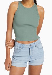 Top corto a coste verde chiaro con scollatura rotonda, abbinato a pantaloni shorts in denim azzurro con risvolti e chiusura a bottone classica.