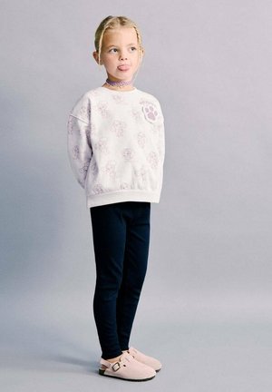 Sweat-shirt blanc avec des imprimés d'animaux rose clair, leggings côtelés bleu marine et chaussures en daim rose à enfiler avec un détail boucle.
