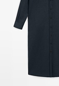 Abito camicia a maniche lunghe blu scuro con sottili righe verticali e bottoni neri sul davanti, maniche risvoltate visibili sul lato sinistro.