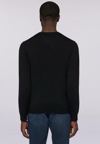 Černý pletený svetr s dlouhými rukávy, kulatým výstřihem a žebrovanými manžetami. Hladká textura, přiléhavý střih, jednoduchý design, bez viditelných vzorů.