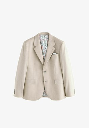 Beige op maat gemaakte blazer met twee knopen, klepzakken, bloemenprint voering en bijpassend bloemenprint pochet op witte achtergrond.