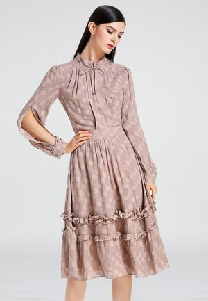 Robe rose poussiéreux avec des manches longues, des accents en volants à l'ourlet, et un motif à carreaux. Elle présente un col haut et un décolleté attaché.