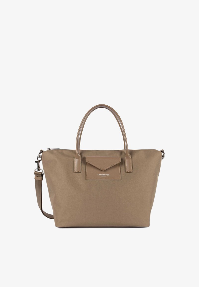 Sac cabas marron avec doubles anses, bandoulière amovible et poche avant à rabat étiquetée « Lancaster Paris ».
