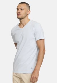 T-shirt en coton bleu clair avec un col en V, des manches courtes et un subtil détail en diamant près de l'ourlet. Texture lisse, coupe décontractée.