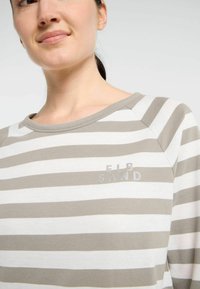 Gestreiftes Langarmshirt in Beige und Weiß. Eingestickter Rundhalsausschnitt und der Text "ELB SAND" in Silber auf der linken Brust. Weiches Baumwollmaterial.