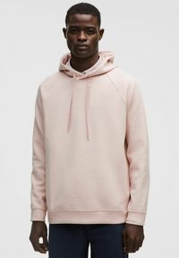 Sudadera de color rosa claro hecha de una tela suave, con capucha con cordones, puños acanalados y un corte relajado. Sin patrones ni logotipos visibles.