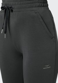Dunkelgraue Jogginghose aus weichem Material mit elastischem Bund. Sie verfügt über zwei Seitentaschen und ein kleines gedrucktes Logo.
