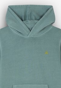 Felpa azzurra chiara con tasca frontale, caratterizzata da un piccolo logo di teschio e ossa incrociate giallo sul petto. Materiale morbido in misto cotone.