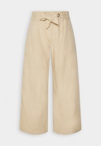 Pantalons larges beiges avec une taille haute, des passants de ceinture et un lien en tissu à la taille. Fabriqués en coton texturé.