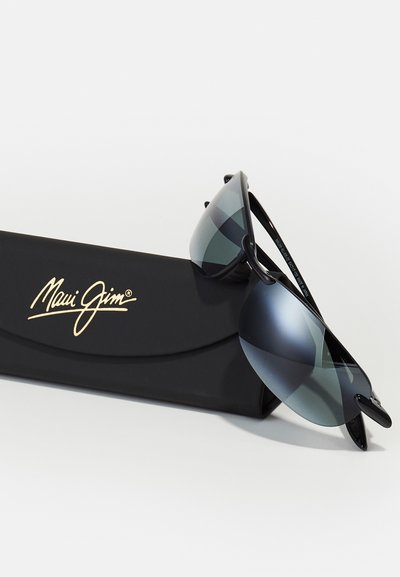 Occhiali da sole Maui Jim neri con design avvolgente, lenti grigio scuro e finitura lucida, esposti su un astuccio nero con logo dorato.