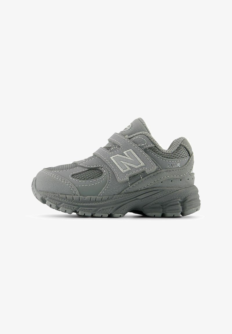 Baskets New Balance 2002R grises avec panneaux en mesh et daim, deux sangles Velcro, semelle rembourrée, et logo "N" de la marque sur le côté.