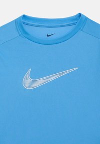 Camisola desportiva azul clara com logótipo Nike swoosh texturizado centrado no peito e um swoosh preto mais pequeno no interior da gola.