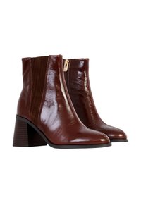 Bottines en cuir marron avec une finition brillante, bout pointu, talon bloc structuré et panneau en tissu texturé sur les côtés. Détail de fermeture éclair dorée.