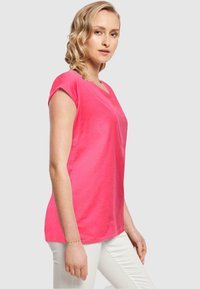 Rosa bomulls t-skjorte med korte ermer, rund hals og en avslappet passform. Stoffet ser mykt og lett ut.