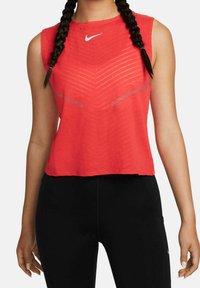 Punainen hihaton urheilupaita, jossa on teksturoidusti kuvioitu pinta, laivastonsininen venekaulus ja pieni valkoinen Nike-logo rinnassa.