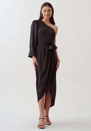 Black one-shoulder dress in silky material, featuring a fitted bodice, flowing sleeve, and a tie waist. Knee-high slit on one side.