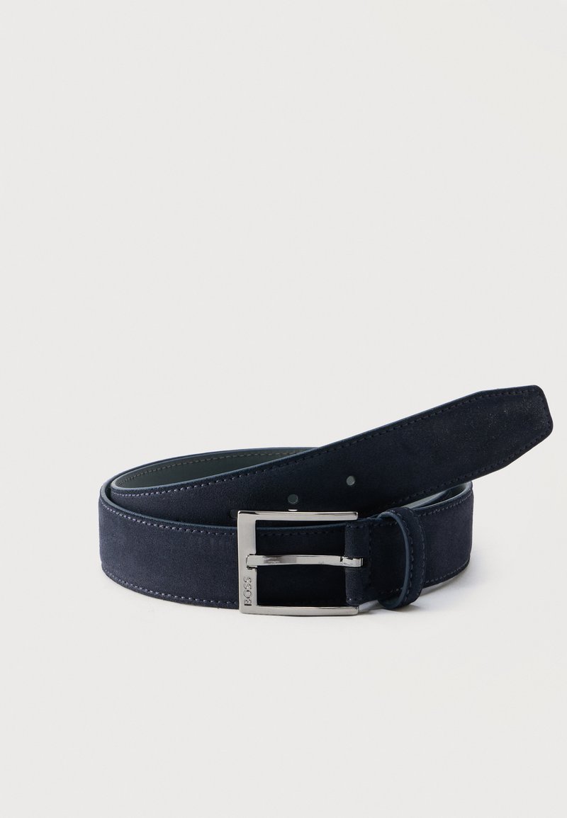 Κυλιόμενη ζώνη από σκούρο μπλε σουέντ με ασημένια ορθογώνια αγκράφα χαραγμένη με την ένδειξη "BOSS" σε απλό φωτεινό φόντο.