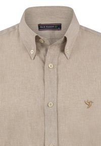 Camisa de lino beige con cuello abotonado, que presenta botones claros y un pequeño logotipo de un pájaro bordado en el lado izquierdo del pecho.