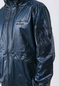 Giubbotto impermeabile blu scuro con zip nera, logo sul petto "PXP," tasca con zip sulla manica e cordini regolabili per il cappuccio.