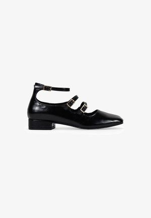 Chaussure en cuir noir avec un bout pointu, un petit talon carré et un design à trois brides avec des boucles dorées. Fini lisse avec une texture brillante.