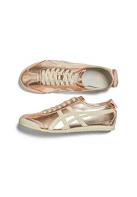 Metalické růžově zlaté tenisky s bílými detaily, které mají texturovaný povrch, kulatou špičku a plochou gumovou podrážku. Šněrování v ladící barvě.