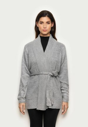 Cardigan en tricot gris avec un design enroulé, manches longues, ceinture latérale et texture côtelée. Il possède un col châle et un ourlet irrégulier.