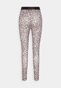 Leggings con estampado de animal en blanco y negro con acentos naranjas. Fabricados con material elástico y una cintura negra ajustada.