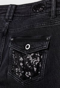 Schwarze Jeans aus Denim mit einer Gesäßtasche aus schwarzen Pailletten, Metallknopfverschluss und strukturiertem Stoff mit gesteppten Details.