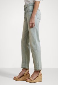 Lyseblå denimjeans med løs passform og rette ben, kombinert med brune espadrillesandaler med ankelrem.