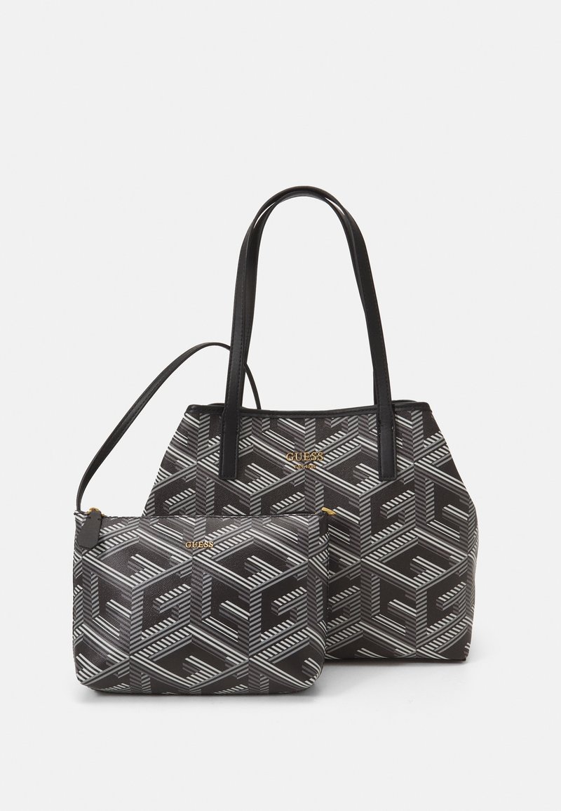 Sac à main Guess noir et gris à motifs et petite pochette assortie avec logo doré et poignées noires, présenté sur fond blanc.