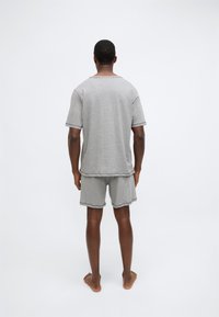 Γκρι βαμβακερό κοντομάνικο T-shirt και ταιριαστά σορτς, με άνετη εφαρμογή και αντίθετες ραφές. Ορατές λεπτομέρειες στα τελειώματα και απαλή υφή.