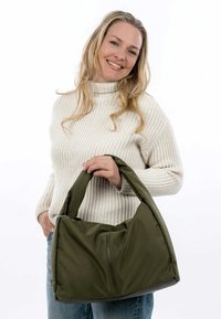 Borsa di stoffa verde oliva morbida con forma arrotondata, manici imbottiti e tasca frontale con zip. Finitura texture con un aspetto leggermente opaco.