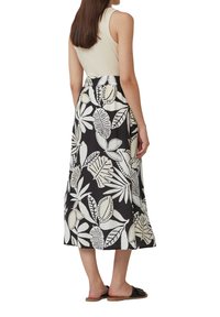 Robe A-line florale à haut crème et jupe noire avec des motifs de feuilles blanches ; fabriquée en tissu doux, longueur cheville, avec une coupe décontractée.