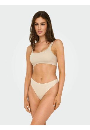 Beige geribbelde crop top en bijpassende thong, met een naadloos ontwerp en brede bandjes, dat een gladde, minimalistische textuur benadrukt.