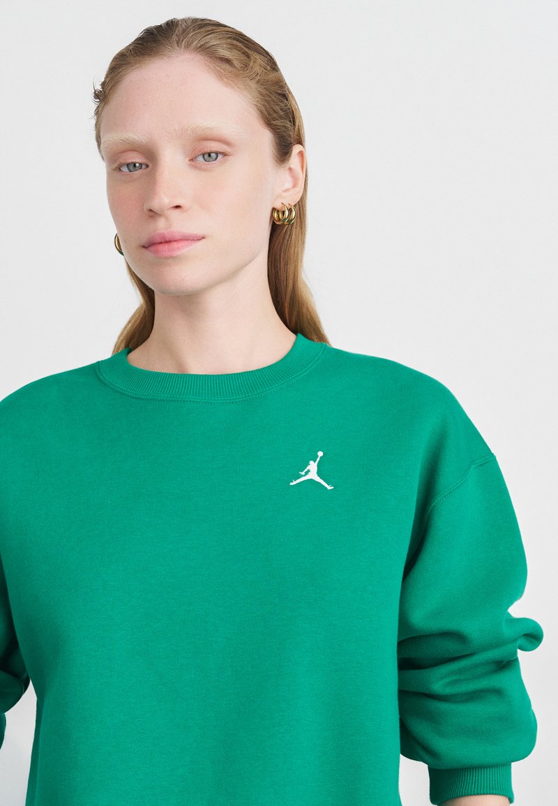Grønn bomullssweatshirt med rund halsutringning, ribbestrikkede mansjetter og hvit Jumpman-logo på venstre bryst. Glatt tekstur og løs passform.