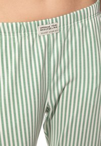 Groen en wit gestreepte pyjamabroek met een zachte katoenen textuur. Elastische tailleband met een label met tekst.