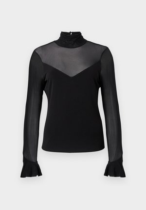 Čierny top s dlhým rukávom a vysokým golierom. Na ramenách priehľadná látka a výstrih v tvare písmena V na hrudi. Rukávy zakončené zvonovými manžetami.
