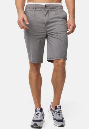Grå knelange shorts lavet af bomuld, med knaplukning, sidelommer og en simpel kant. Båret med grå sportssko.